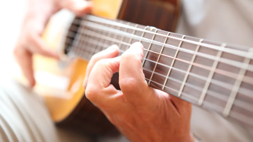 Eine Hand greift Akkorde auf einer Gitarre.