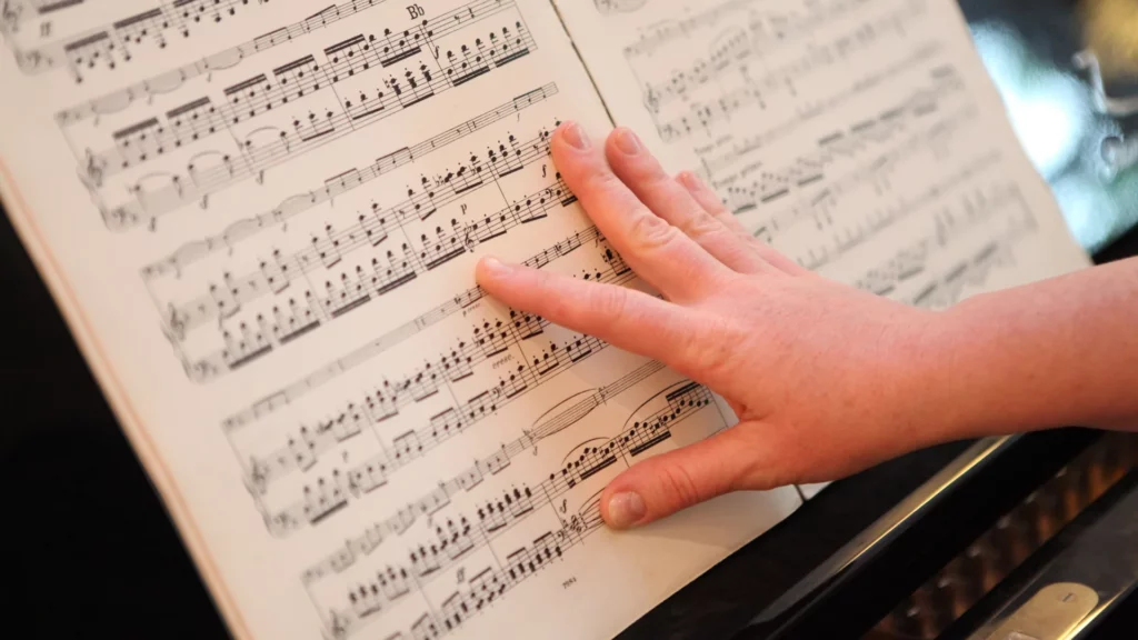 Eine Hand zeigt auf Noten am Klavier.